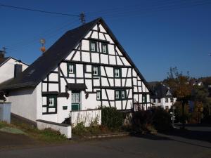 ein weißes und schwarzes Haus mit schwarzem Dach in der Unterkunft Ferienwohnung Zauberhaft in Schalkenmehren