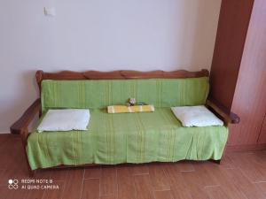 a green bed with two pillows on top of it at Mary's apartments in Kiáton