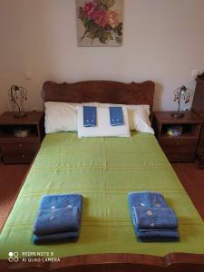 a bedroom with a green bed with two blue folders at Mary's apartments in Kiáton