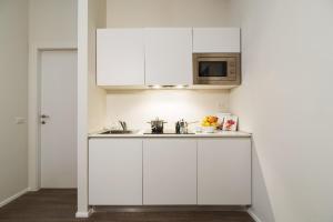 cocina blanca con fregadero y microondas en Contempora Apartments - Cavallotti 13 - B12a en Milán