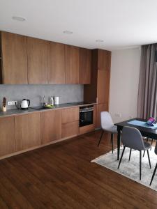 - une cuisine avec des placards en bois, une table et des chaises dans l'établissement Centro apartamentai, à Birštonas