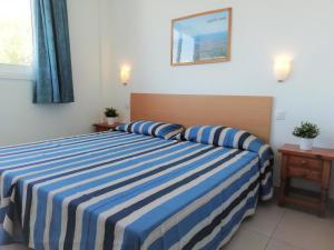 a bedroom with a blue and white striped bed at Trill Mirasol C primera linea mar L'Estartit in L'Estartit