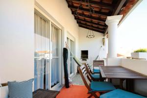 a balcony with a table and chairs and a window at Apartamento Vizir in Vila Nova de Milfontes