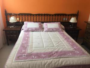 Una cama grande con sábanas rosas y almohadas. en A Postiña, en Areas
