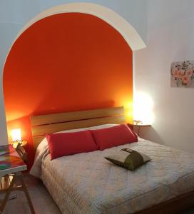 a bedroom with a bed with an orange wall at Casa Sant'Anna 24 in Ragusa