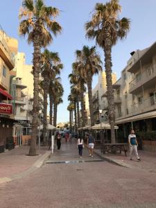 a group of people walking down a street with palm trees at Ocean Pearl Apartment no4 in St Paul's Bay