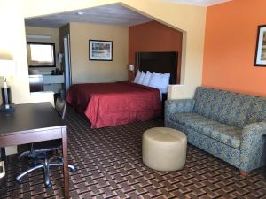 a hotel room with a bed and a desk and a chair at La Grange Executive Inn and Suites in La Grange