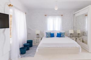 a white bedroom with a white bed and blue pillows at Sugar Blue in Mikonos +60 photos