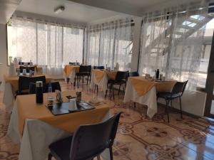 a dining room with tables and chairs and windows at Hotel Pulmahue in Copiapó