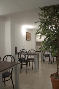 una sala da pranzo con tavoli, sedie e un albero in vaso di Hostel Malva a Łomianki