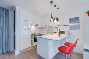 a kitchen with white cabinets and a red chair at Sa Maniga 3i in Cala Millor