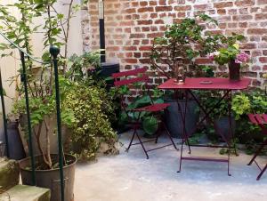 lapetitemaisondeparis في باريس: طاولة حمراء وكراسي في حديقة بها نباتات