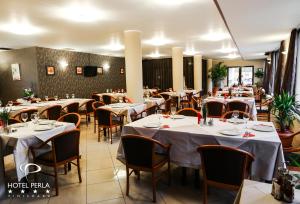 una sala da pranzo con tavoli e sedie bianchi di Hotel Perla a Timişoara