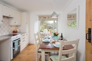 uma cozinha com uma mesa de madeira com cadeiras e uma mesa e uma sala de jantar em Willowherb and Foxglove Cottages Hawick em Hawick