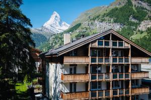um edifício com uma montanha ao fundo em Hotel Holiday em Zermatt