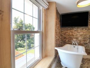 een badkamer met een groot raam en een wit bad bij Rosebank Cottage in Woolacombe +43 foto's