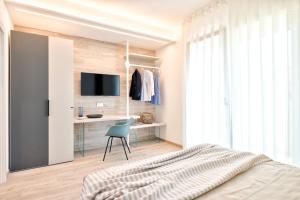 a bedroom with a bed and a desk with a tv at Albamarina Residence in Sottomarina