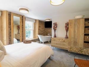 een slaapkamer met een wit bed en een badkuip bij Rosebank Cottage in Woolacombe