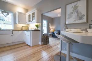 a kitchen with white cabinets and a table in it at Bay Tree Cottage in Hillsborough
