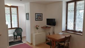un salon avec une table et une télévision dans l'établissement VILLA ASTAY, Studio No. 3 - Rez de chaussée, à Aix-les-Bains
