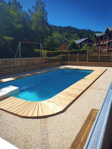 une piscine avec une terrasse en bois et un ballon de football dans l'établissement L'Ours Blanc, à La Féclaz