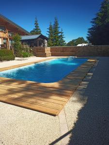 a swimming pool with a wooden deck next to a house at L'Ours Blanc in La Féclaz
