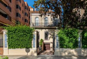 an old building with a balcony and two bushes at Villa Alfonso, Restored Palace House with gardens and Monuments Views in Seville