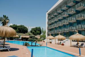un gran edificio con piscina y sombrillas en Sol Port Cambrils Hotel en Cambrils
