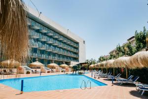 a hotel with a swimming pool with chairs and umbrellas at Sol Port Cambrils Hotel in Cambrils