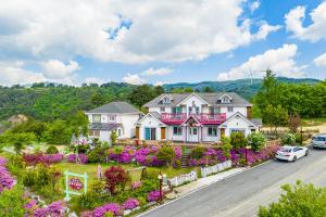 a large house with purple flowers in the yard at Pungcha & Herb Pension in Pyeongchang