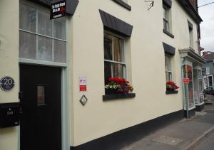 a white building with flowers in windows and a door at The Poppy House in Bishops Castle