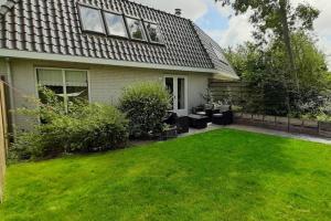 una casa con un patio con césped verde en Holiday Home de witte raaf with garden and hottub en Noordwijk aan Zee