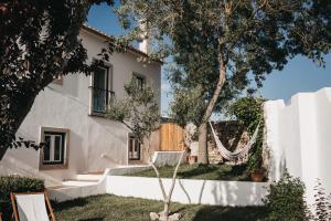 a house with a tree in the yard at Casa dos Junqueiros - Countryside Guest House in Caldas da Rainha