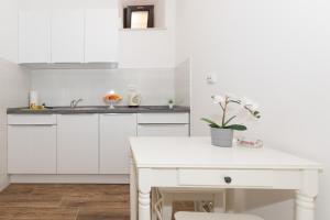 Apartments Santa Maria في دوبروفنيك: مطبخ بدولاب بيضاء وطاولة بيضاء