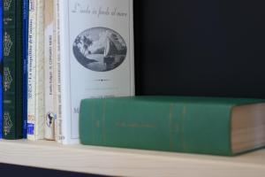 ein Grünbuch auf einem Regal mit anderen Büchern in der Unterkunft Elementa in Conversano