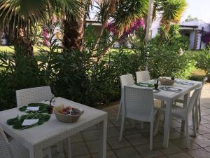 duas mesas e cadeiras com comida num pátio em Valle di Mare Country Resort em Fontane Bianche