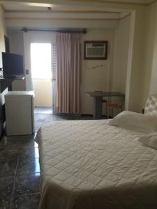 1 dormitorio con cama, mesa y ventana en Perea Hotel, en São Carlos