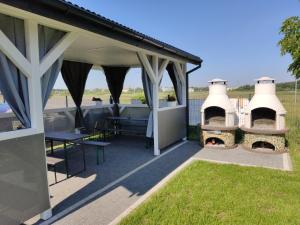 a covered patio with a grill and a table and chairs at Aurora Ustka-Przewłoka in Ustka
