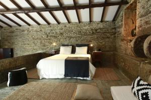 - une chambre avec un lit dans une pièce en pierre dans l'établissement CASA da PISCINA, Quinta do Espinho, Douro Valley, à Tabuaço
