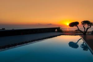 a swimming pool with a sunset in the background at San Marino Suites by Calm Collection in Fira