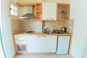 a small kitchen with white cabinets and a sink at Avra Sea View Paradise Pool Apartments in Moraitika