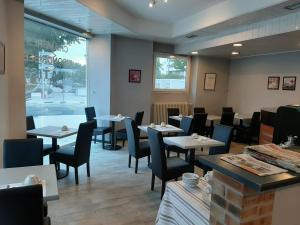 Un comedor con mesas y sillas y una ventana. en Le Royalty, en Angers