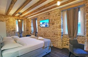 a bedroom with a bed and a stone wall at Pearl Stone Apartments in Šibenik