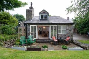 a cottage with a table and chairs in a yard at Finest Retreats - The Cottage - Luxury 1 Bed Cottage in Rhydymwyn