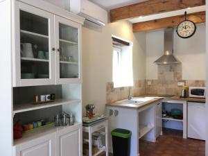 a kitchen with white cabinets and a clock on the wall at gite la magnanerie in Réauville