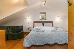 1 dormitorio con 1 cama y 1 sofá verde en Finest Retreats - The Cottage - Luxury 1 Bed Cottage, en Rhydymwyn
