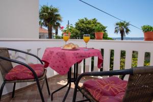 a table with two glasses of orange juice on a balcony at Apartman Tradicija in Kaštela