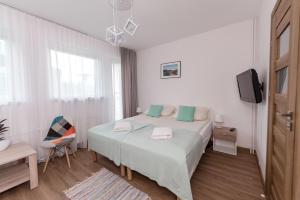1 dormitorio blanco con 1 cama y TV en Willa Biały Domek, en Ustroń
