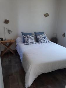 - une chambre avec un grand lit blanc et des oreillers bleus dans l'établissement Maisonnette proche de la plage, à Tarnos