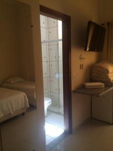 a bedroom with a bathroom with a toilet and a television at Perea Hotel in São Carlos
